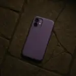 Purple smartphone case lying abandoned on a cracked dungeon floor under warm torchlight.